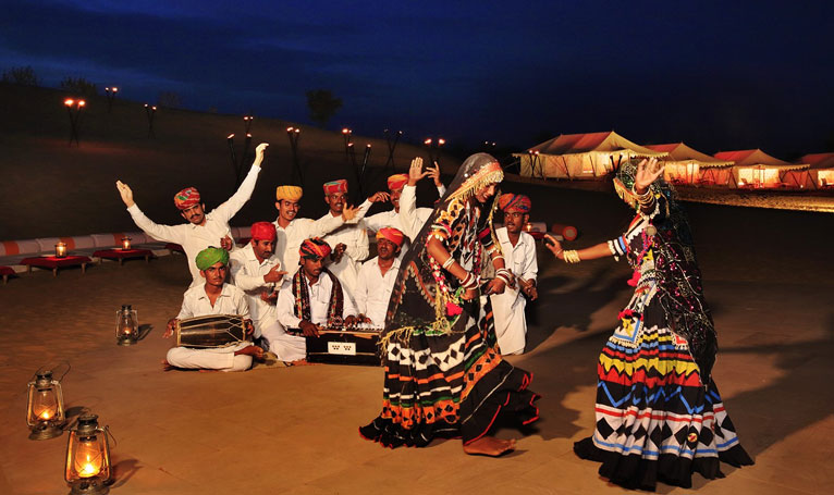 Rajasthani folk dancers performing beside desert camp tents